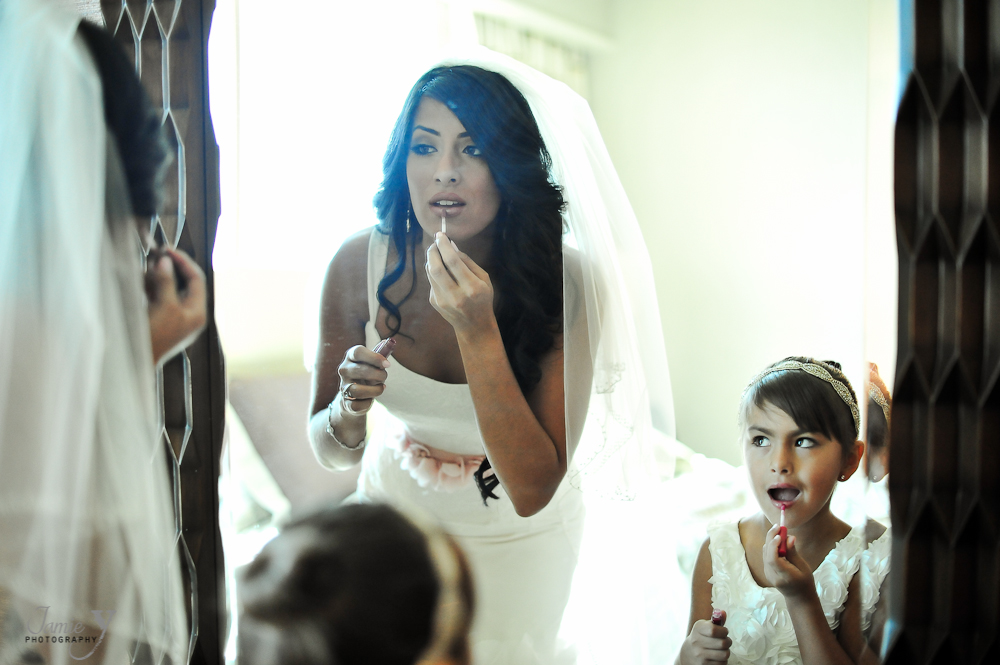 bride and flower girl putting on lipstick in mirror mother and daughter wedding day