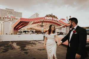 bride and groom in front of circus circus with pink cadillac car