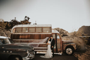 bride and groom standing in front of a red bus at nelson nevada