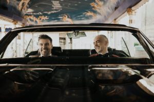 two grooms in drive thru wedding at little white chapel in vintage convertible car