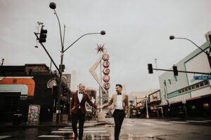 two grooms walking by vegas neon sign in downtown las vegas
