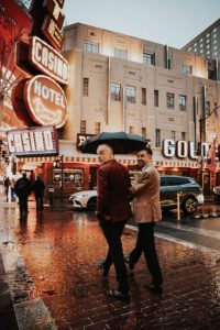two grooms walking among neon lights of las vegas downtown after wedding